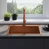 A copper sink and faucet are shown in a kitchen setting with plants and a window view. Produktbild-Vorschau