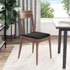 A wooden chair with a black cushion sits on a white rug next to a dining table, with a large window and greenery in the background. Podgląd zdjęcia produktu