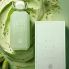 A perfume bottle and its box are displayed on a green background with pistachio-like elements. Náhled obrázku produktu