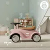 A pink ride-on car for children is shown in a nursery or playroom setting, with toys and a teepee in the background. Produktbild-Vorschau