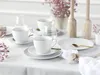 A table setting with white porcelain cups and saucers, gold spoons, and pink flowers. Náhľad obrázku produktu