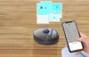 A robot vacuum cleaner is shown on a wooden floor next to a smartphone displaying an app interface. Náhľad obrázku produktu