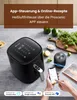 A black air fryer is shown on a countertop with various ingredients and a smartphone displaying an app interface. Produktbild-Vorschau