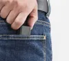 A hand is putting a small gray charger into the back pocket of blue jeans. Produktbild-Vorschau