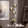 A dining table set with cups and a vase of flowers, under three pendant lights. Produktbild-Vorschau
