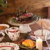 A festive Christmas table setting with a chocolate cake, cheese, grapes, and hot drinks. Náhled obrázku produktu