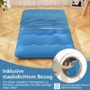 A blue mattress on a wooden floor, with a close-up of a washing machine in the corner. Produktbild-Vorschau