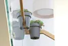 Two gray planters with flowers are mounted on a wooden structure, reflected in a glass surface. Náhled obrázku produktu