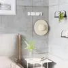 A modern bedroom corner with a hook rack holding a hat, a bedside table with books and a vase of greenery, and a bed in the foreground. Podgląd zdjęcia produktu