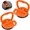 Two orange suction cup dent pullers are displayed against a white background. A small inset image shows a hand using one of the suction cups to lift a screen. Produktbild-Vorschau