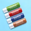 Four Vaseline lip balm tubes are arranged diagonally on a light blue background. Produktbild-Vorschau