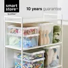 A white shelving unit filled with transparent storage boxes containing toys and other items. A green dinosaur toy is visible on the top shelf. Produktbild-Vorschau