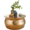 A round, hammered gold coffee table with decorative items on top. Voir les images du produit