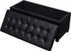 A black upholstered storage ottoman with its lid open, revealing the interior storage space. The ottoman is shown from a slightly elevated side angle against a white background. Podgląd zdjęcia produktu