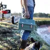 A person holding a green lunch box in an outdoor setting with a dog nearby. Podgląd zdjęcia produktu