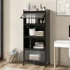 A black metal shelving unit with multiple shelves, some open and some with doors, is shown in a room setting next to a white desk. Produktbild-Vorschau