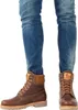 A person wearing blue jeans and brown leather boots. Anteprima dell’immagine prodotto