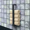 A black metal towel rack with four rolled beige towels attached, mounted on a tiled wall. Anteprima dell’immagine prodotto