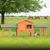 A wooden rabbit hutch with two rabbits in a grassy field with horses in the background. Produktbild-Vorschau