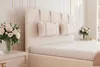 A close-up view of a bed with a cream-colored headboard and pillows. Náhled obrázku produktu