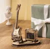 A wooden model of an electric guitar and amplifier are displayed on a wooden surface, with a gift box in the background. Voir les images du produit