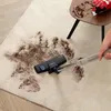 A vacuum cleaner is being used to clean up a spill on a rug next to a small table. Produktbild-Vorschau