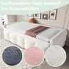 A white sofa bed with a brown blanket on top, displayed in a room with framed pictures on the wall. Three circular swatches of different fabric textures (gray, pink, and white) are shown in the foreground. Produktbild-Vorschau