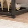 A close-up view of a shoe rack with beige high-heeled shoes on it, placed on a wooden floor next to a rug. Náhľad obrázku produktu