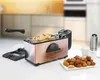 A copper-colored deep fryer with a basket of french fries, along with a plate of fried snacks, a small bowl of sauce, and a salt grinder, placed on a white countertop with a blurred kitchen background. Produktbild-Vorschau