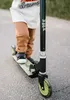 A child is riding a scooter outdoors on a paved path. Produktbild-Vorschau