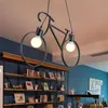 A bicycle-shaped pendant light hangs above a bookshelf filled with books and decorative items in a room with blue walls. Podgląd zdjęcia produktu