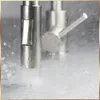 A close-up shot of a kitchen faucet with water spraying. Produktbild-Vorschau