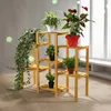 A wooden plant stand with several potted plants on it, placed indoors near a window. Produktbild-Vorschau