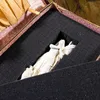 A white figurine is placed inside a black foam-lined box. Produktbild-Vorschau
