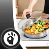 A person is cooking vegetables in a pan on a stovetop, with a glass lid partially open. Voir les images du produit