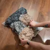 Hands are shown compressing a vacuum-sealed bag filled with clothes on a wooden floor. Náhľad obrázku produktu