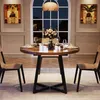 A round dining table with chairs set in a dining room with a large window and artwork on the walls. Podgląd zdjęcia produktu