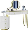A white vanity table with gold accents and a round LED mirror, shown with a matching side cabinet and decorative items. Náhled obrázku produktu