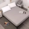 A bed with a gray fitted sheet and two white pillows, with a magazine and headphones on the bed. Produktbild-Vorschau