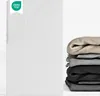 A white fitted sheet is shown on the left, with a stack of folded sheets in various colors on the right. Produktbild-Vorschau