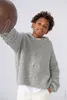 A young boy is holding a brown ball and wearing a gray knitted hoodie. Produktbild-Vorschau
