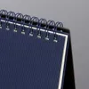 A close-up view of the spiral binding and textured cover of a desk calendar. Podgląd zdjęcia produktu