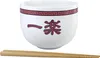 A white ramen bowl with red Japanese characters and a decorative red border, placed in front of a white background. A pair of wooden chopsticks rests below the bowl. Podgląd zdjęcia produktu