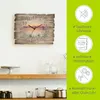 A wall clock with a beach sunset scene is displayed on a white wall above two wooden shelves with kitchenware. Produktbild-Vorschau