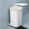 A white trash can with a lid is mounted on a light blue wall. Produktbild-Vorschau