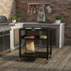 An outdoor kitchen scene with a grill and a black rolling cart. Náhľad obrázku produktu