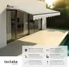 An awning is extended over a patio area next to a house with sliding glass doors. Náhled obrázku produktu