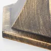 A close-up view of the textured surface of a black and gold outdoor lamp base. Náhled obrázku produktu