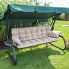 A garden swing chair with cushions is placed on a grassy lawn, with plants and a fence in the background. Náhled obrázku produktu