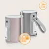 Two portable bottle warmers, one pink and one gray, are displayed against a light beige background. A circular overlay in the foreground shows a locked padlock with flames and a checkmark, symbolizing safety and protection. Another circular overlay in the  Produktbild-Vorschau